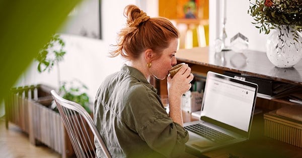 Dame drikker kaffe og jobber på datamaskin, til illustrasjon for betale til utlandet
