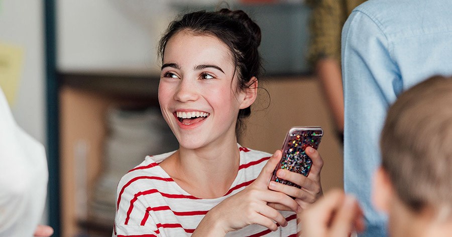Ung jente holder en mobiltelefon, til illustrasjon for BankID for ungdom