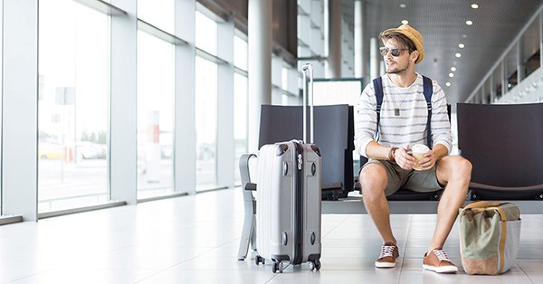 Mann sitter på flyplass i sommerklær, til illustrasjon for konto
