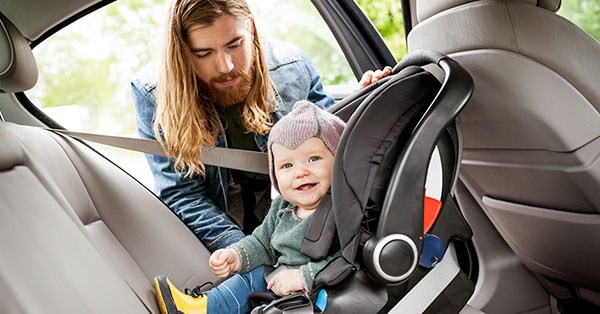 Mann putter barn i bilsete i ny bil, til illustrasjon for billån