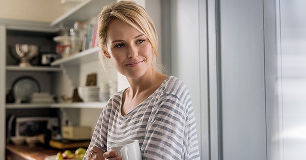 Kvinne står på kjøkkenet og holder en kaffekopp, til illustrasjon for nedbetalingsplan