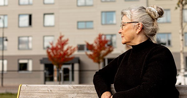 Voksen dame sitter på benk ute, til illustrasjon for seniorlån