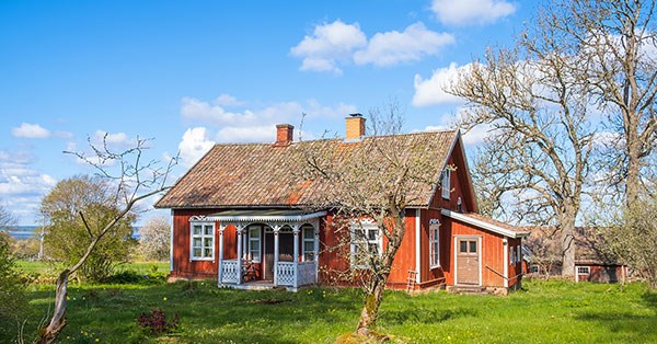 Rødt sommerhus med behov for vedlikehold i norsk landskap
