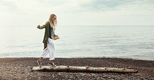 Dame balanserer på stokk ved stranden, til illustrasjon for feriepenger