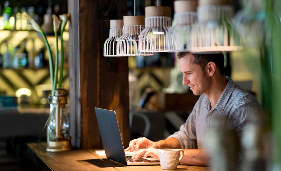 Mann sitter på cafe og ser på laptop