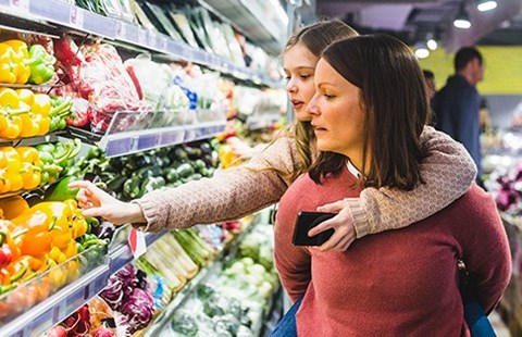 Kvinne og ung jente handler på dagligvarebutikk, til illustrasjon for å spare penger